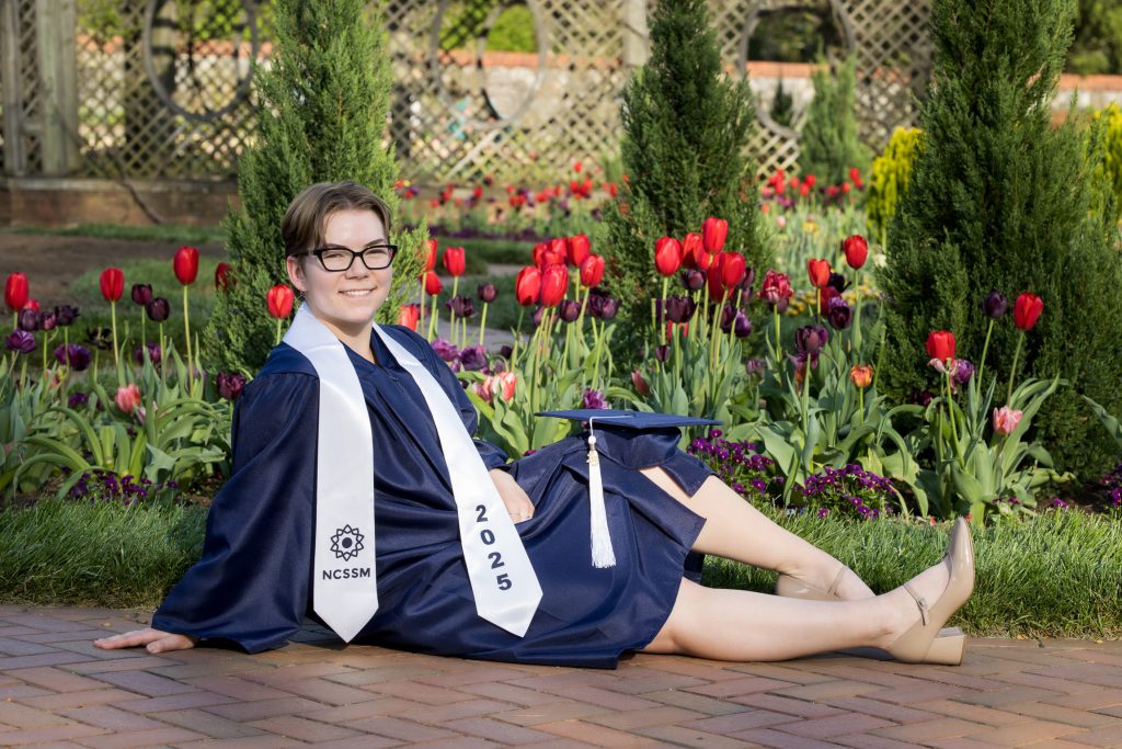 High school senior in cap and gown during an outdoor graduation portrait session.